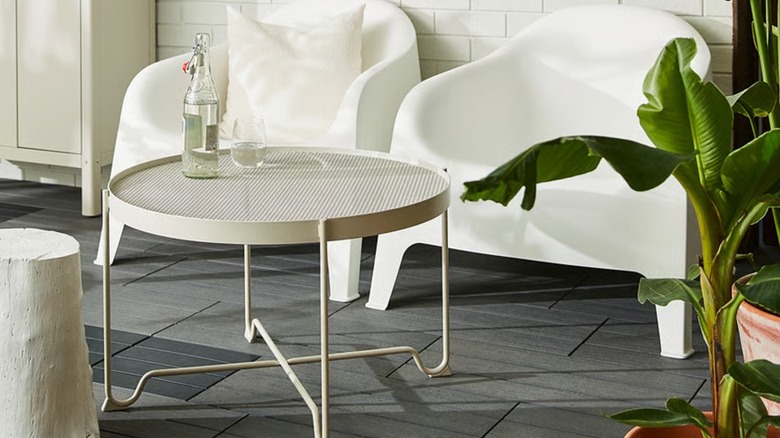 A white mesh table placed in front of large white chairs