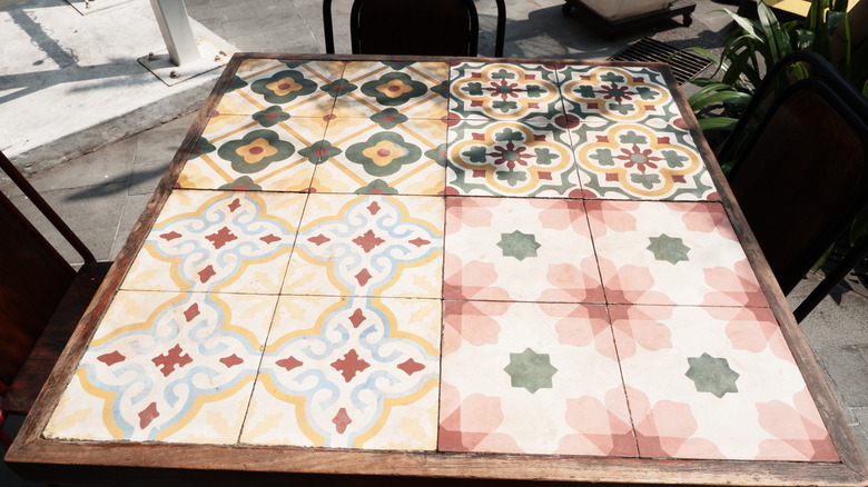 A square-tiled wooden table outside on a paved patio.