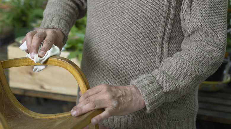 Man's hands wiping wood furniture