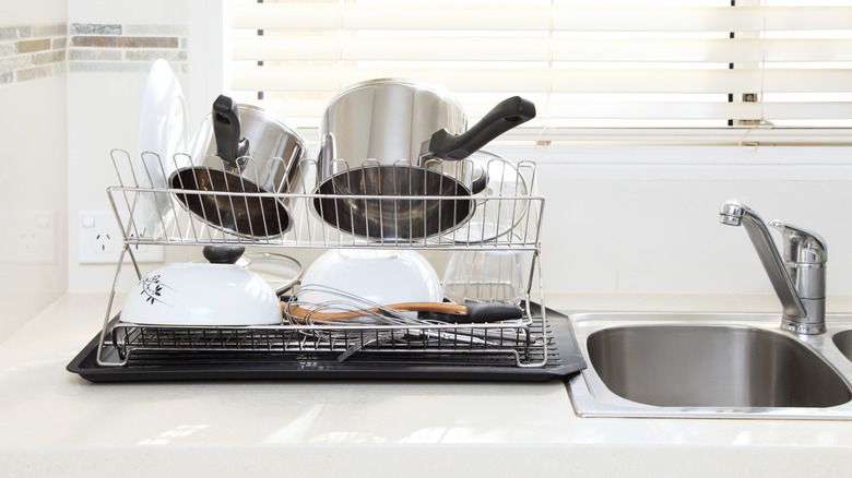 Bulky dish rack on countertop with dishes on it next to the sink.