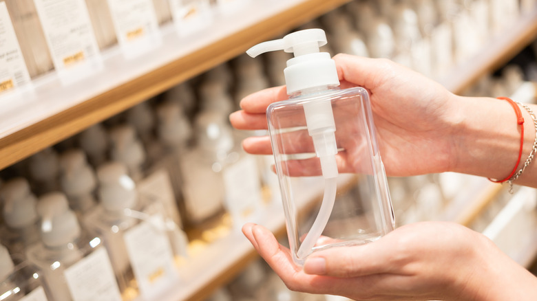 A person holds a plastic soap bottle with a pump