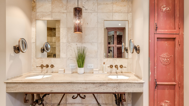 Light beige bathroom with stone furnishings and a red door