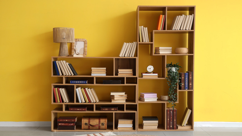 A wooden bookshelf in front of a bright yellow wall