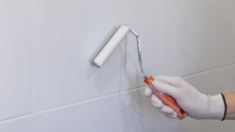 Hand painting tiles in the kitchen with a roller