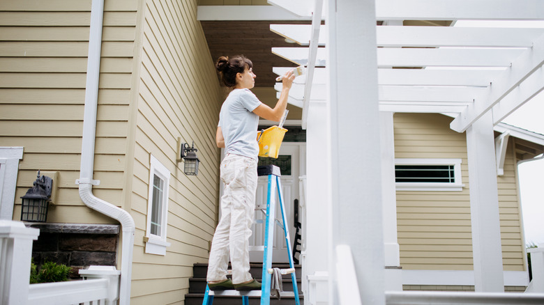 Woman painting pergola white