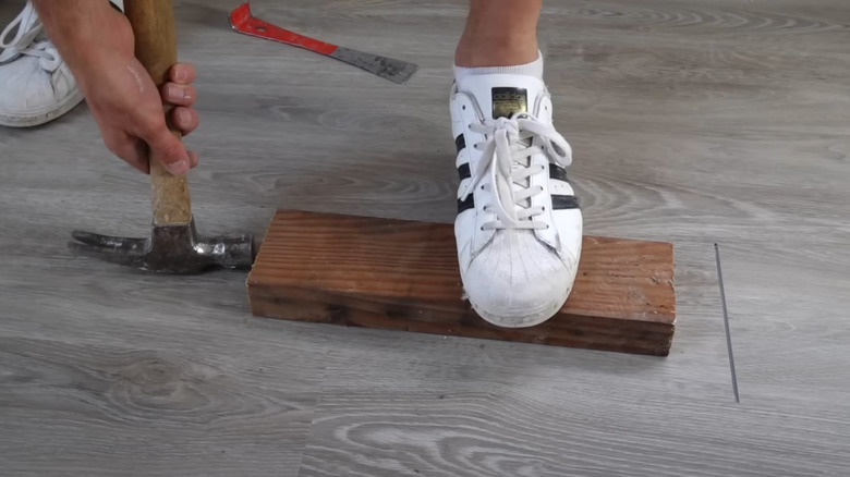 Closing a gap in vinyl plank flooring with a 2x4 and the "blue and glue" trick