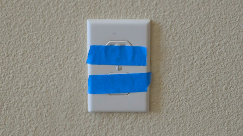 An electrical receptacle masked with painter's tape