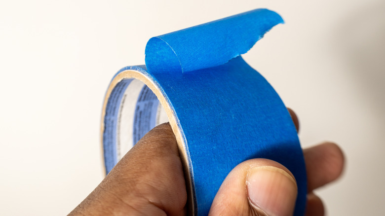 Hand holding a roll of blue painter's tape