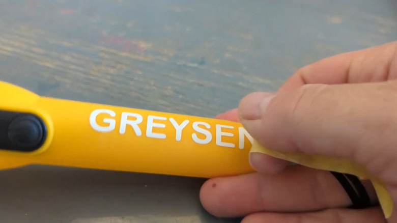 Adhering vinyl letters to a flashlight using painter's tape as transfer tape