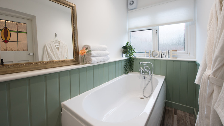 Bathroom with sage panelled walls surrounding bathtub