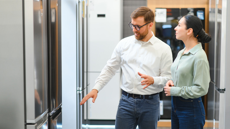 A man and woman look at a refrigerator display