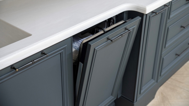 A built-in dishwasher is disguised behind navy blue cabinetry