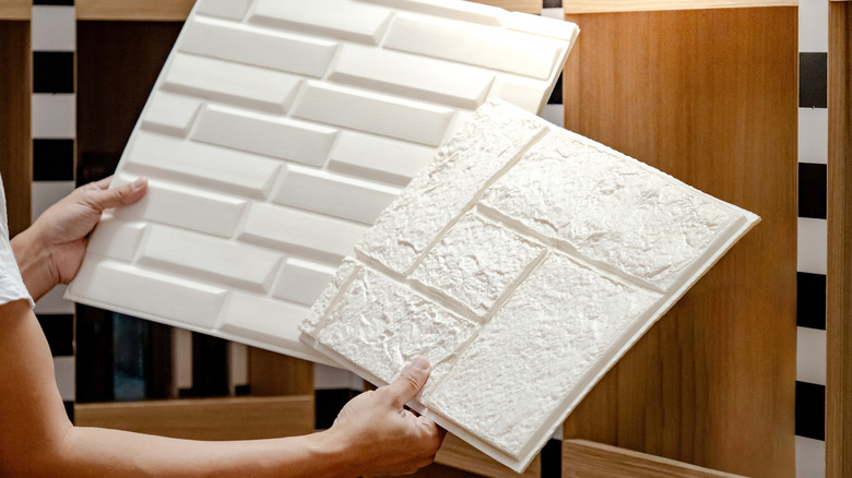 Person holding and comparing texturized wall panels.