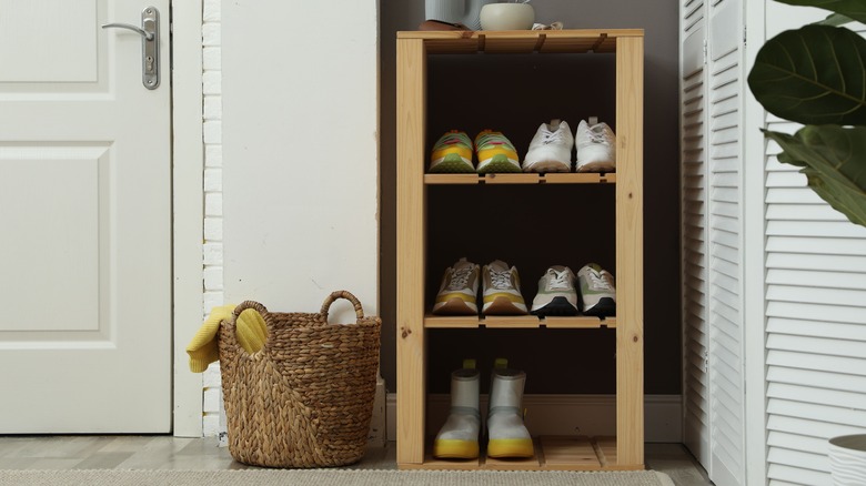 A basket sits next to a shoe rack in an entryway.