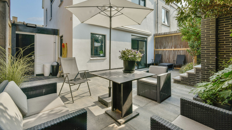 An outdoor patio with gray furniture, and lots of angular hardscaping.