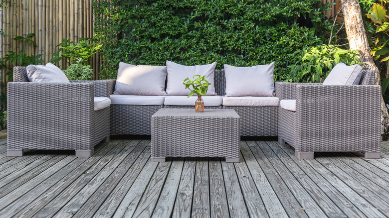 A large terrace with matching rattan furniture, including sofas, chairs, and a table.