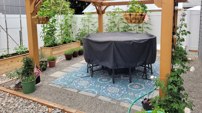 a pea gravel patio under a pergola with river rock edging