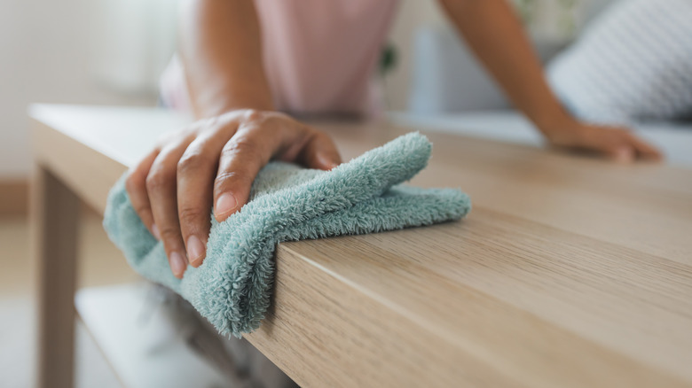 person cleaning table with rag