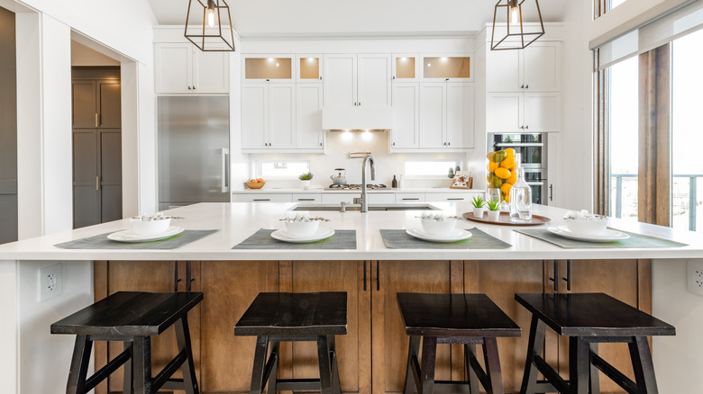 Island with wooden stools in white kitchen