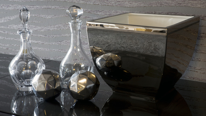 Decorative chrome balls and bowl on table next to glass bottles