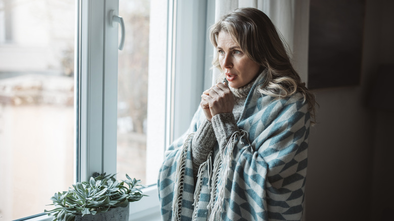 Person wrapped in blanket near window