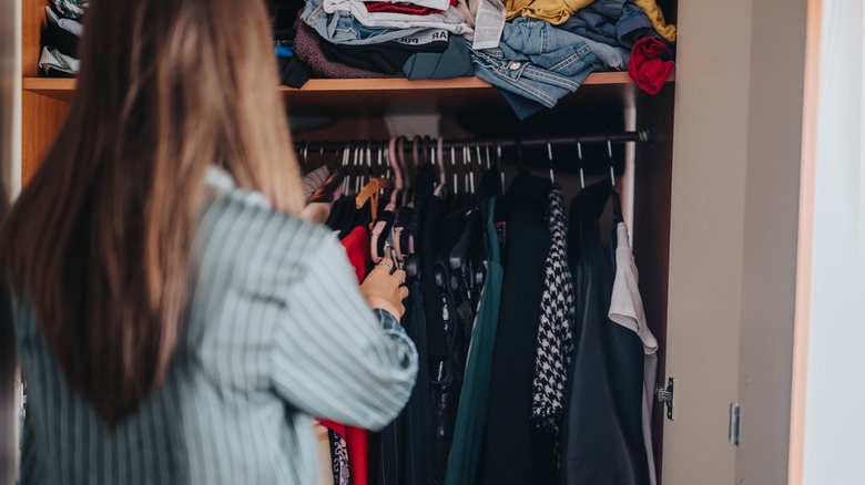 A woman organizes a closet full of clothes