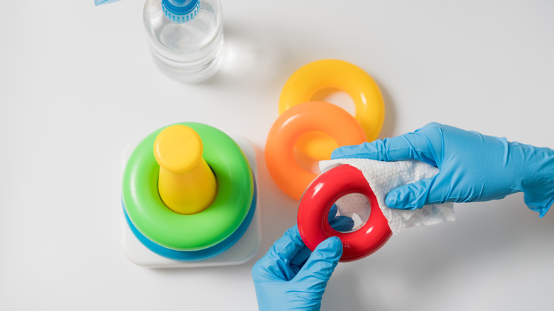 Hands in blue gloves cleaning kids' toys.