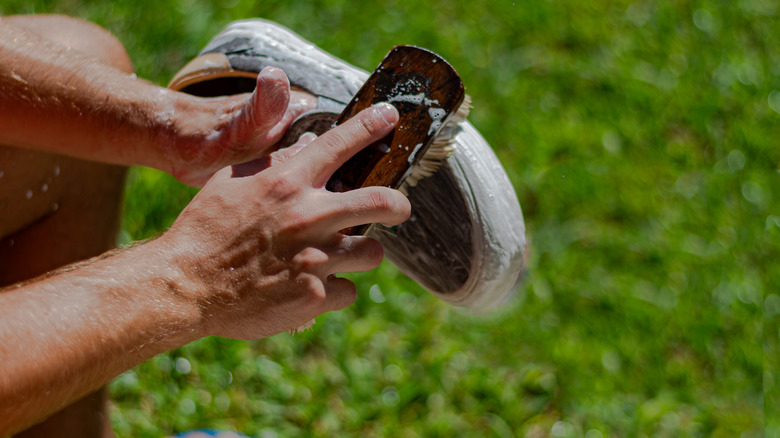 Person scrubbing sports shoes in back yard.