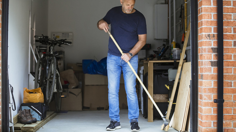 A man sweeping the floor of his garage.