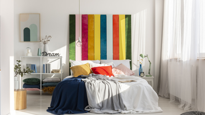 A bed with a tall rainbow-colored upholstered headboard