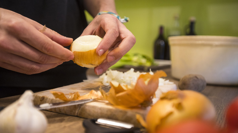 Person removing skin from a raw onion in a kitchen