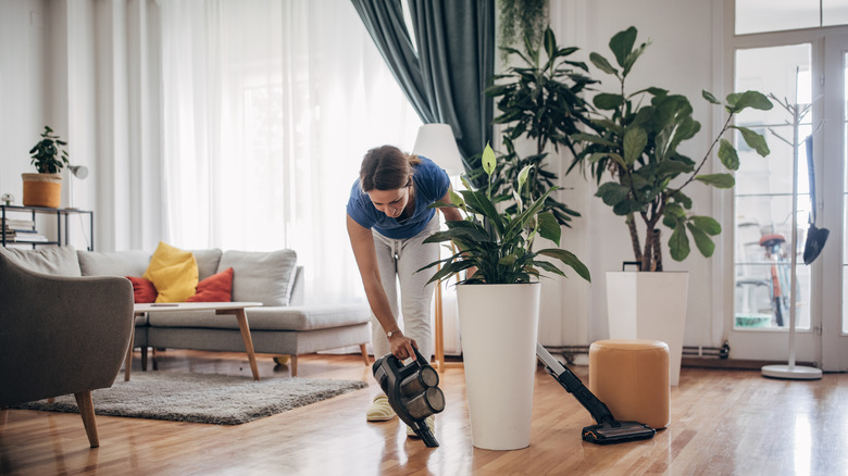 Woman vacuuming floor near plants