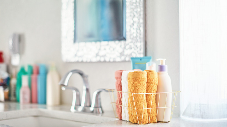 A bathroom counter with many bottles and shower supplies on it