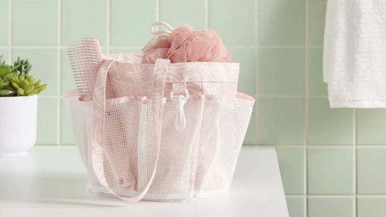 A pink mesh shower caddy on a bathroom counter