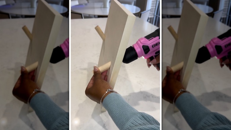 person using a drill to screw dowels onto a wooden base base