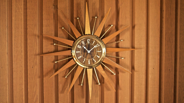 A teak starburst clock on a wood wall