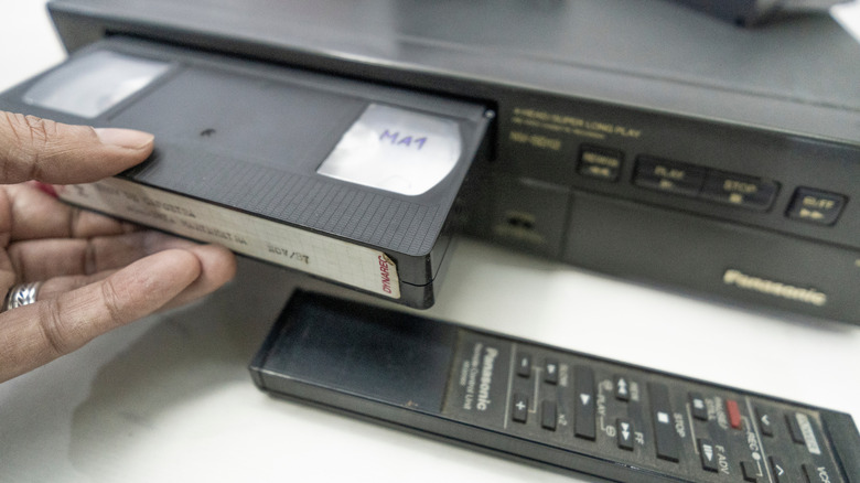 Person putting in a VHS tape into a player