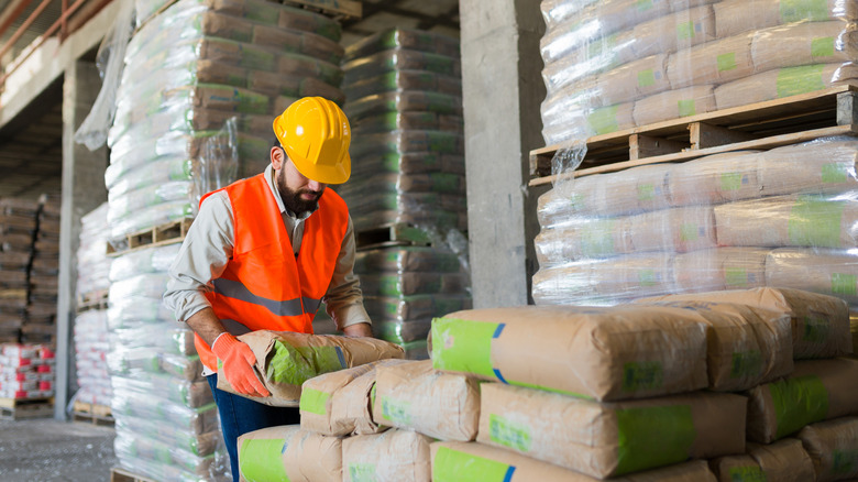 Worker stacking bags of cement in warehouse