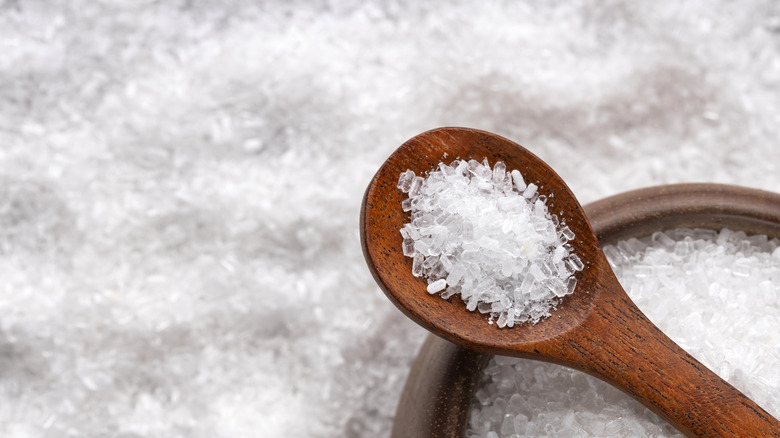 Epsom salt sits in a wooden spoon above a bowl.