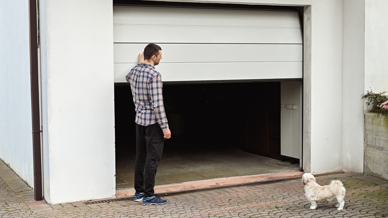 Person opening a white garage door from the outside