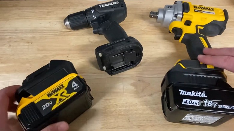 Dewalt and Makita drills with attached adapters and swapped batteries