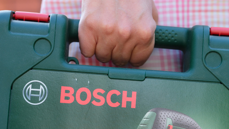 Close-up shot of woman holding tool case with Bosch jigsaw in it.