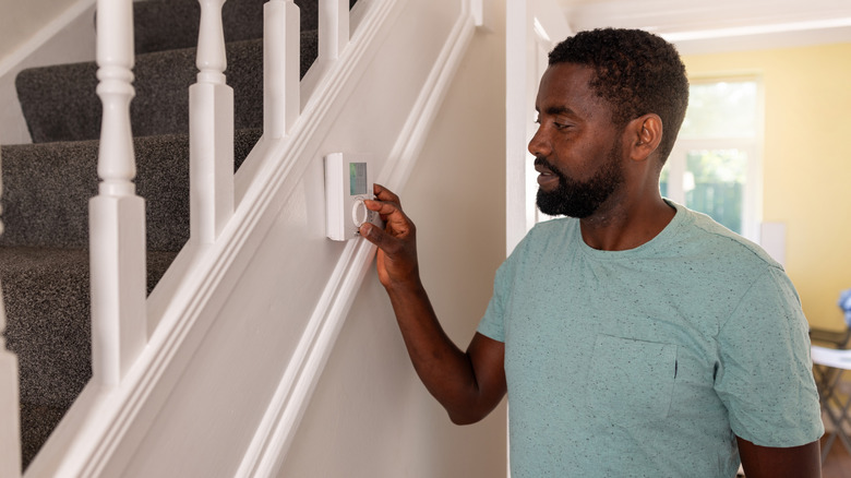 Man adjusts his thermostat to precool his home during off-peak hours