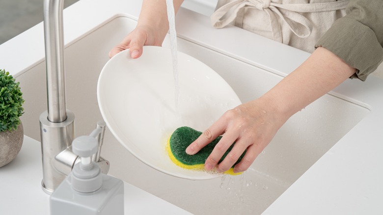 Woman rinsing white dish