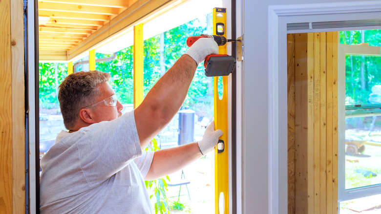 a man uses a level to ensure that his door will swing properly