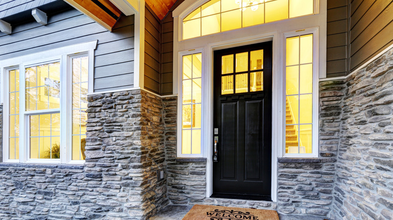 a dark front entry door of a home stands out against the backlit windows