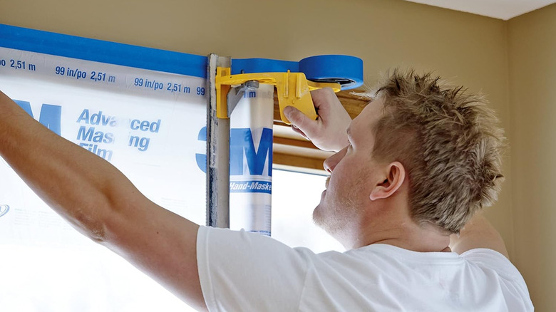 Man putting up paint tape and masking film