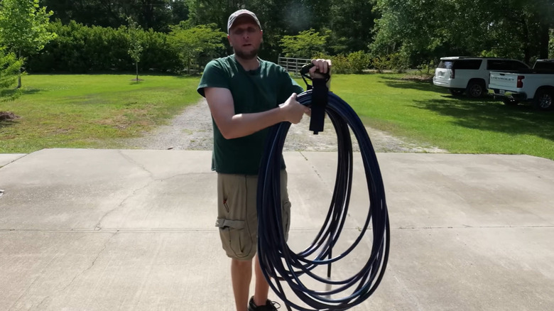 A man holding a coiled garden hose