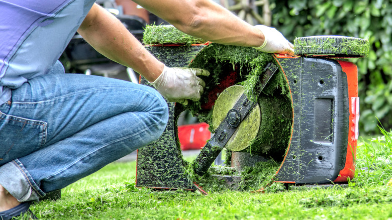 Person working on an overturned lawn mower