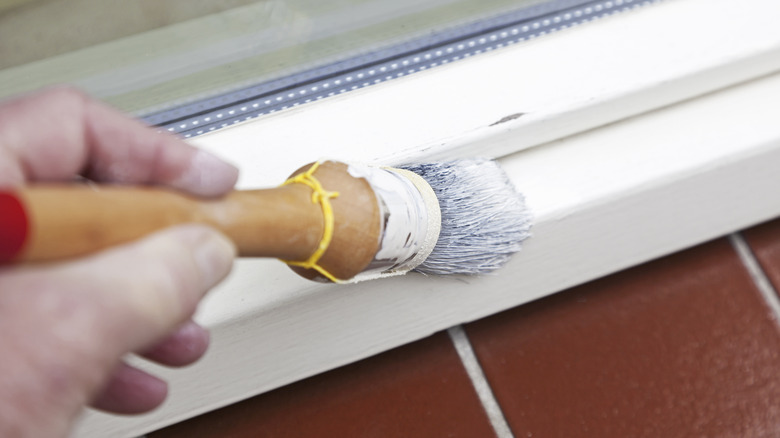 Man painting window sill white